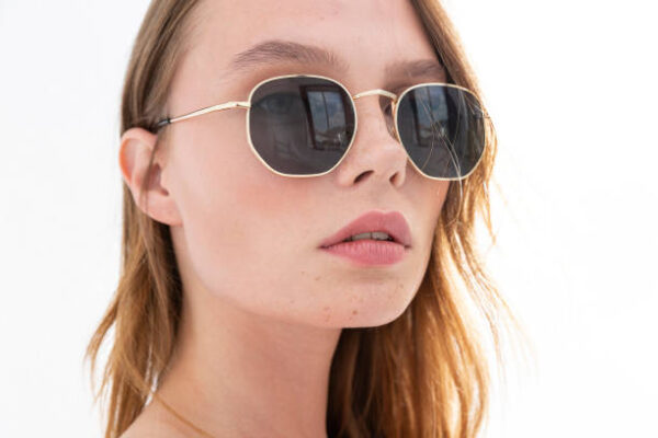 Blonde freckled girl wearing sunglasses. photo studio with sunlight.