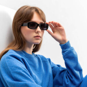 Young girl in blue tracksuit and black boots lying on cube isolated on white