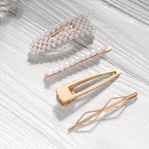 Golden with pearls hairpin clip set on white wooden background